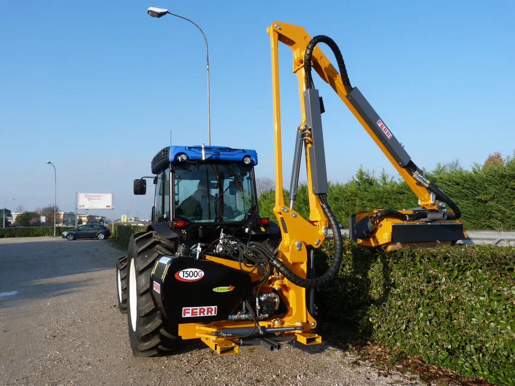 Braç desbrossador Ferri T 500 G retallant una tanca vegetal a la vora d'una carretera