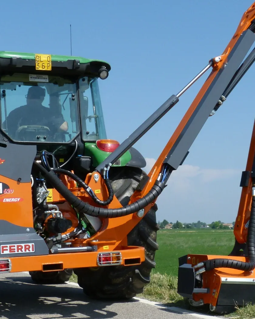 Capçal trinxador Ferri a l'extrem d'un braç desbrossador, segant el marge herbós, amb el tractor al costat
