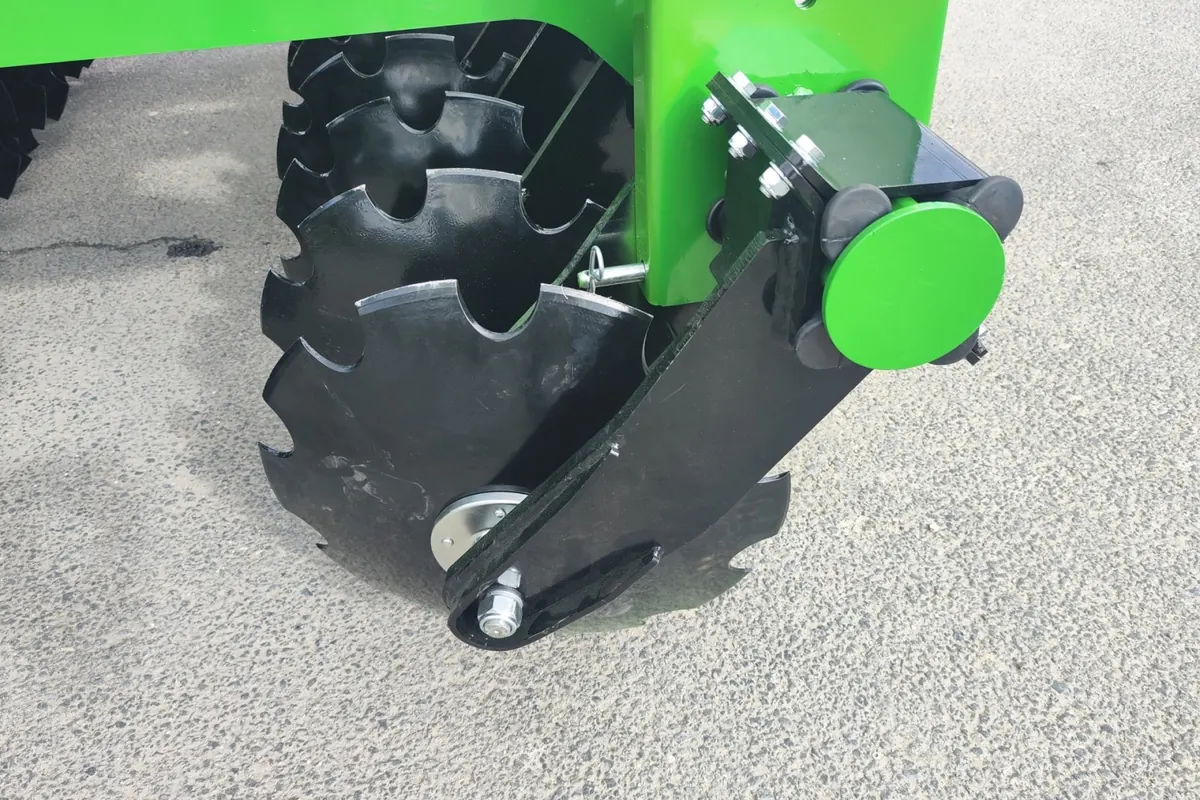 Primer pla d'un disc dentat muntat al seu braç, amb els elements de goma de la suspensió a la fixació, sobre asfalt