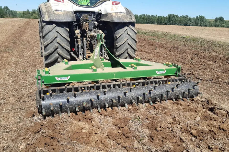 Subsolador Gaher amb corró treballant un camp llaurat, vist des del darrere d'un tractor