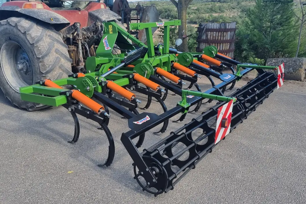 Xissel plegable Gaher desplegat darrere d'un tractor vermell, sobre asfalt, amb els senyals vermells i blancs a les puntes