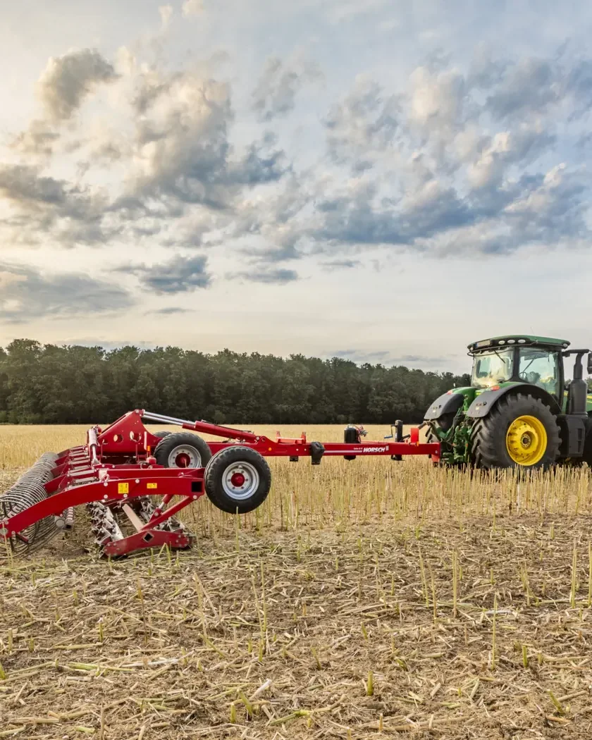 Corró de ganivetes Horsch Cultro desplegat darrere d'un tractor verd, sobre un camp de rostoll
