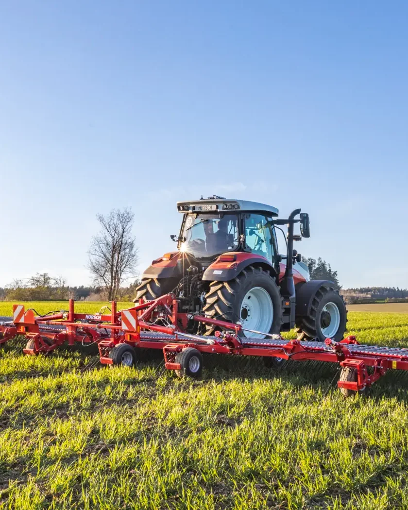 Rascle Horsch Cura desplegat darrere d'un tractor vermell, passant per sobre d'un camp de cereal acabat de néixer