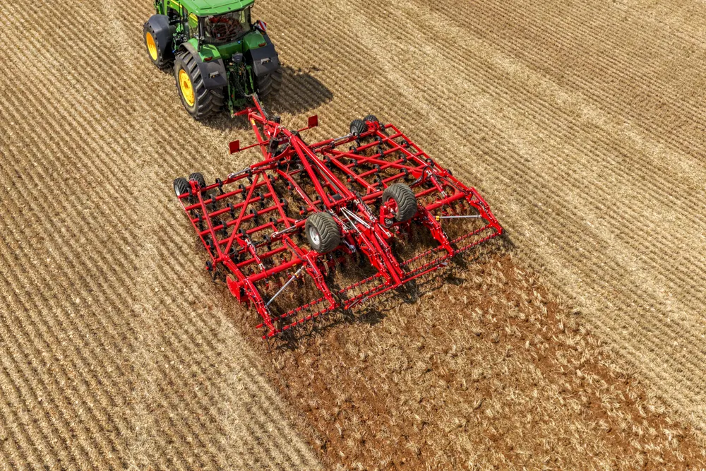 Vista des de dalt d'un tractor verd amb el Finer desplegat treballant el rostoll, amb la franja acabada de treballar al darrere