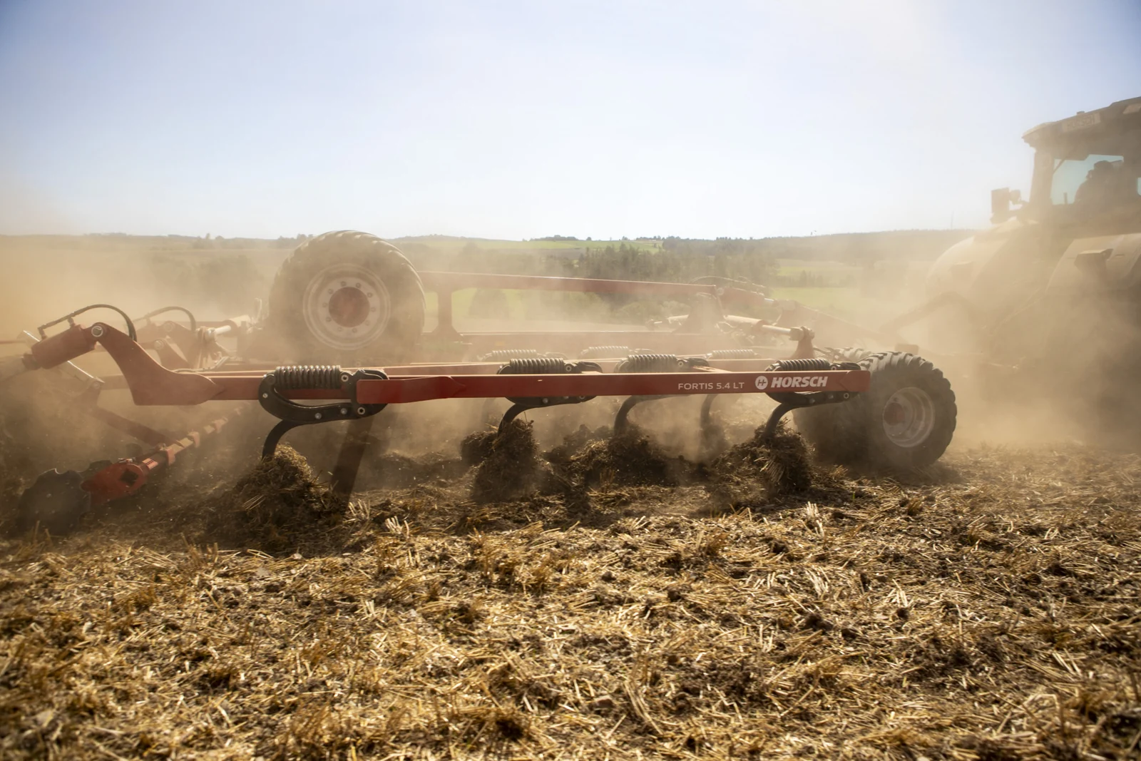 Pues del Fortis remenant la palla i la terra en ple treball, amb el tractor entre la pols al fons