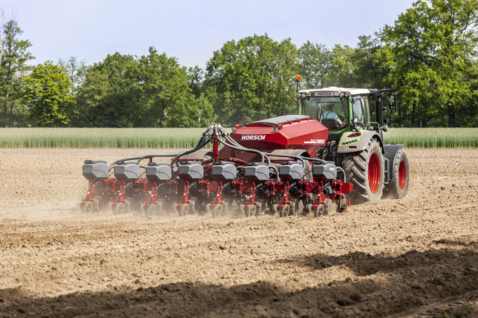 Sembradora Horsch Maestro de prop darrere d'un tractor verd, amb els elements de sembra alineats