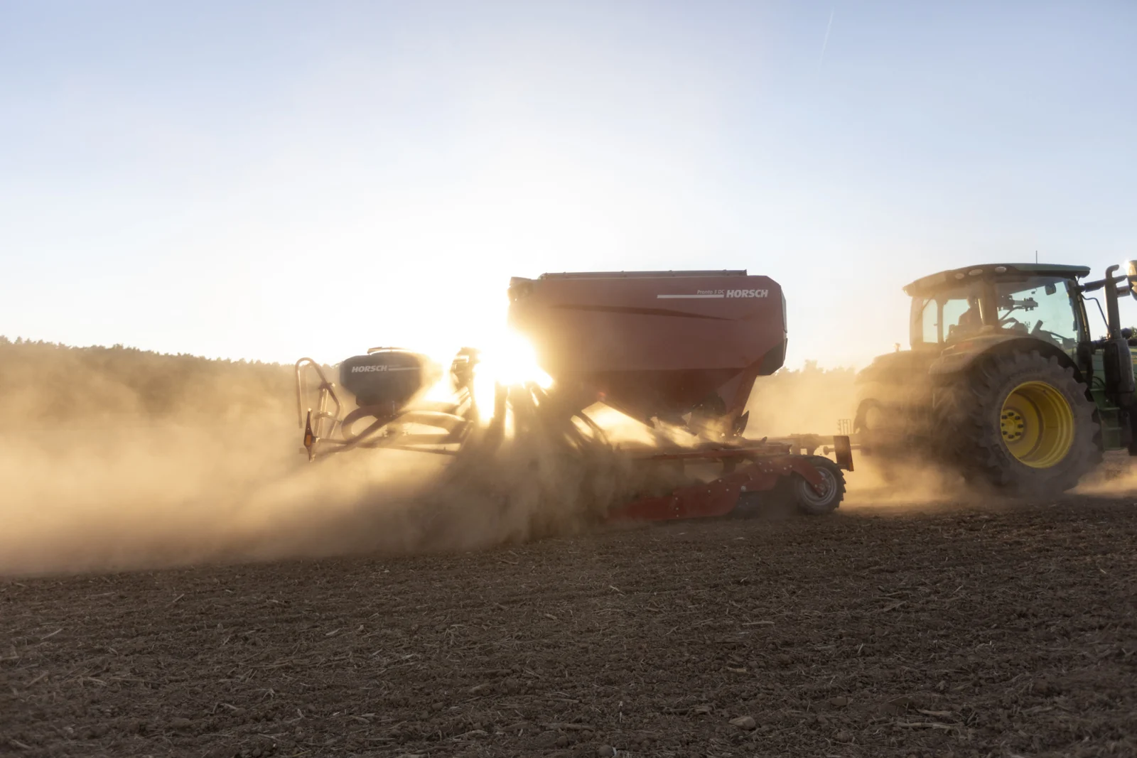 Sembradora Horsch Pronto sembrant entre un núvol de pols, amb el tractor a contrallum