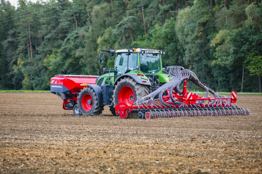 Sembradora Horsch Taro SL amb el tractor sobre terra preparada, amb bosc al fons