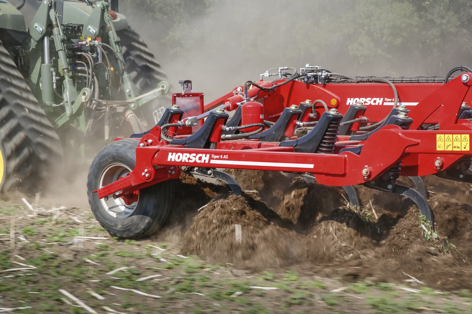 Primer pla del bastidor d'un Tiger 6 AS amb el nom llegible i les pues obrint la terra, darrere d'un tractor d'erugues