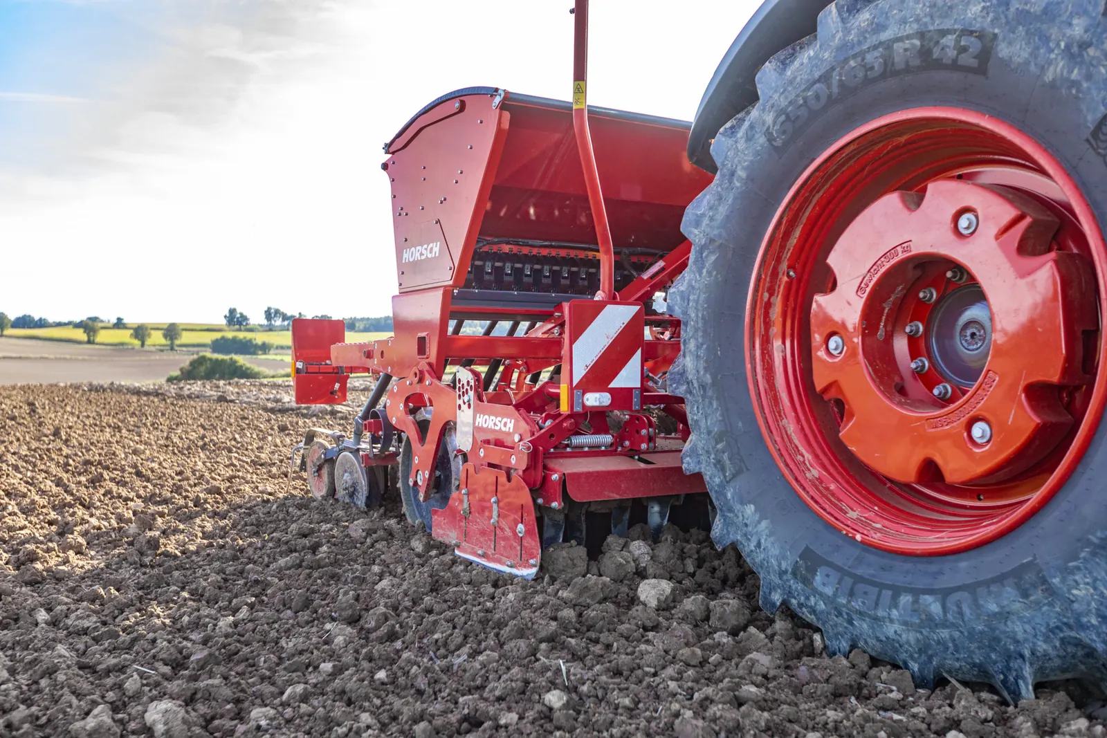 Primer pla de la roda del tractor amb la Versa al darrere, sobre un sòl de terrossos