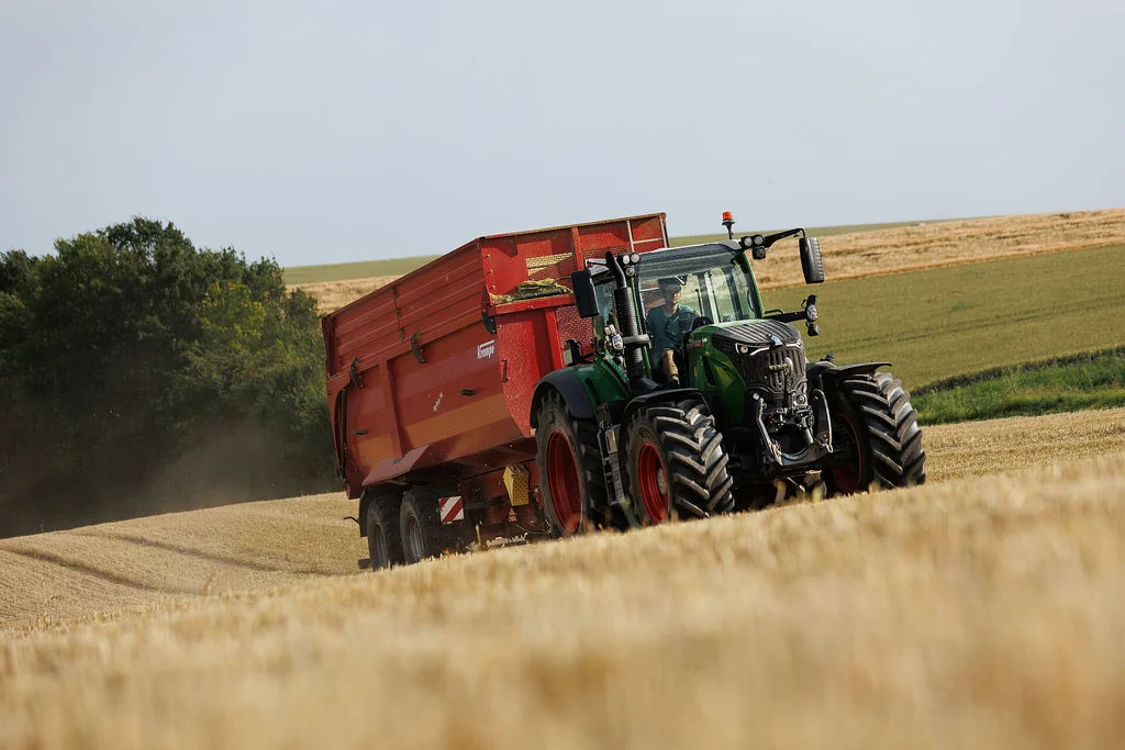Tractor fosc estirant una banyera Krampe BigBody 790 per un camp de rostoll de cereal