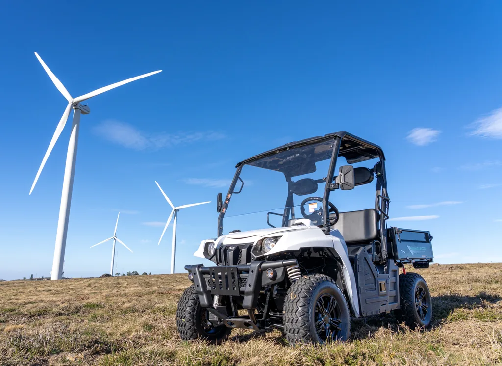 Vehicle utilitari Linhai sencer al camp, amb els aerogeneradors al fons