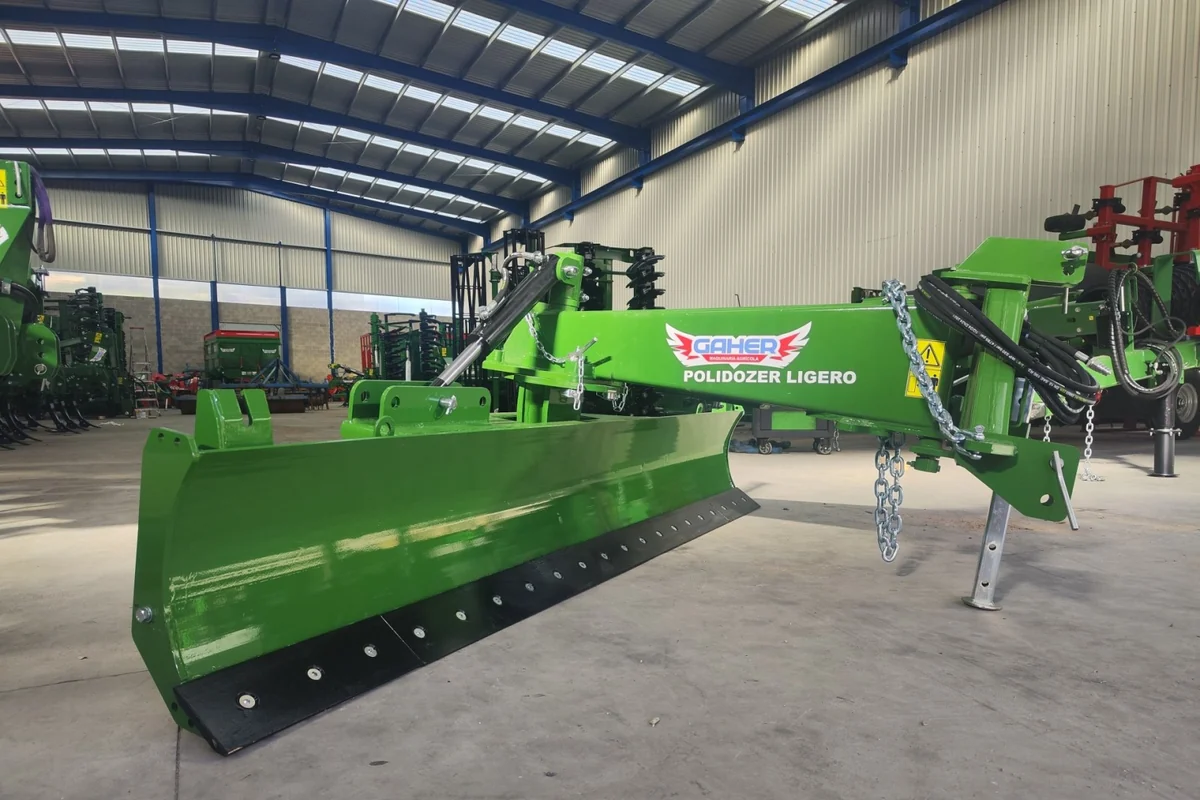 Pala polidozer Gaher amb el rètol «Polidozer ligero» al braç, aturada sobre les seves potes dins d'una nau