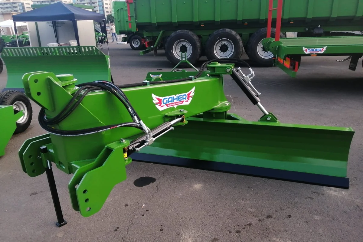 Pala polidozer Gaher verda sobre asfalt, amb remolcs aparcats al darrere