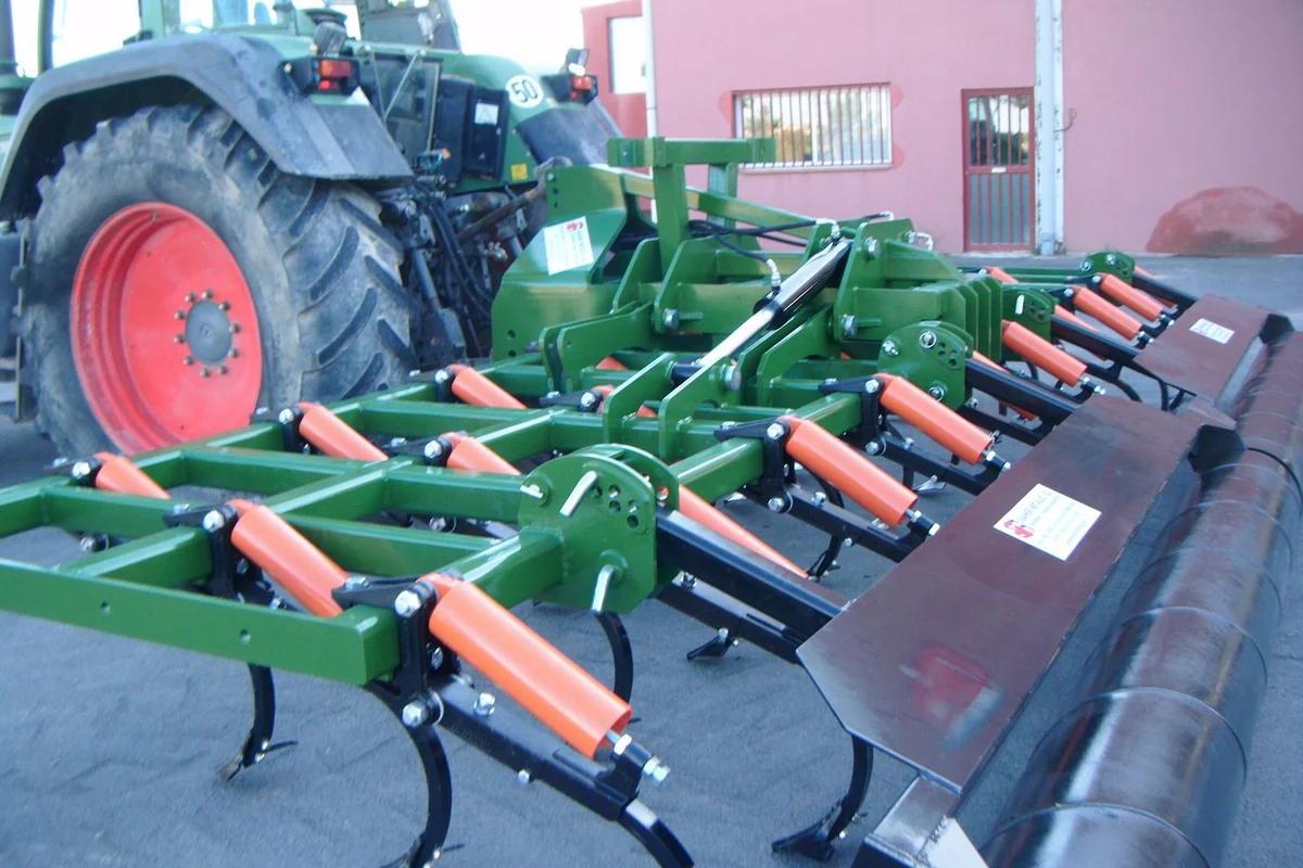 Semixissel Gaher desplegat darrere d'un tractor de rodes vermelles, davant d'una nau, amb els braços i el corró al darrere