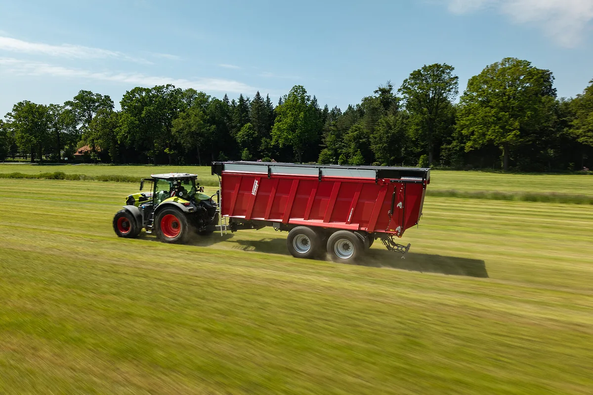 Tractor verd clar estirant un remolc Krampe RamBody 750 per un prat segat
