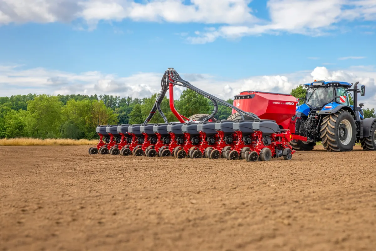 Sembradora Horsch Maestro 12 TX amb la filera d'elements de sembra desplegada, darrere d'un tractor blau