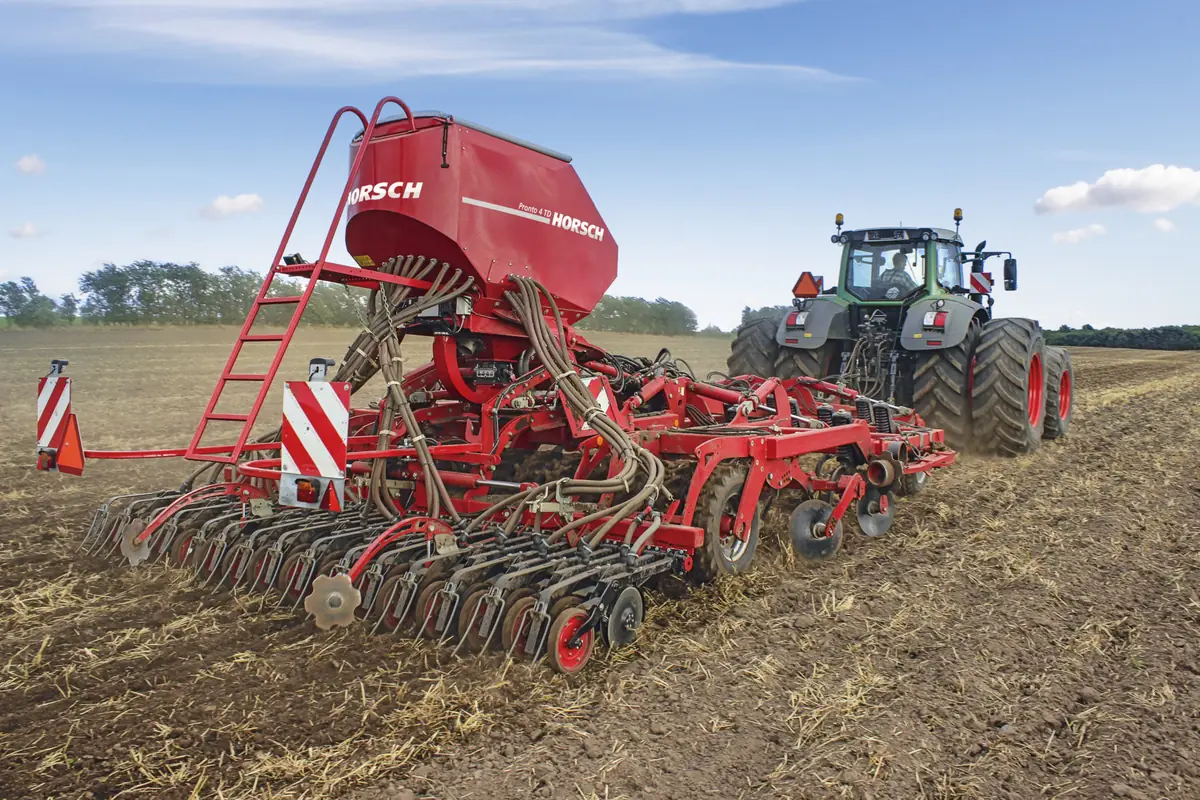 Sembradora Horsch Pronto TD vista de tres quarts pel darrere sobre rostoll, amb les relles de disc a primer terme i el tractor al fons