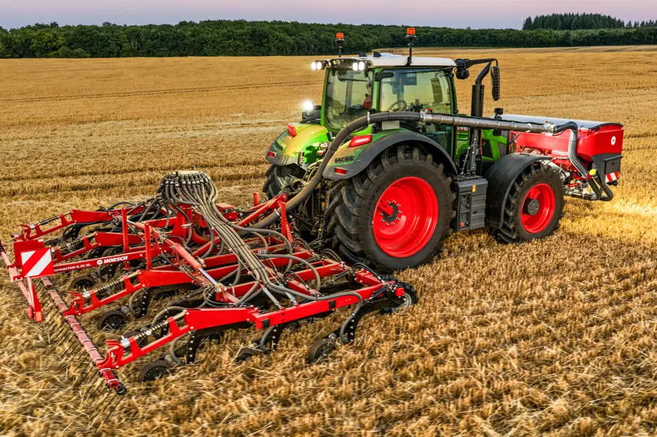 Sembradora Horsch Sprinter SL amb la barra de pues desplegada darrere d'un tractor verd, sobre rostoll