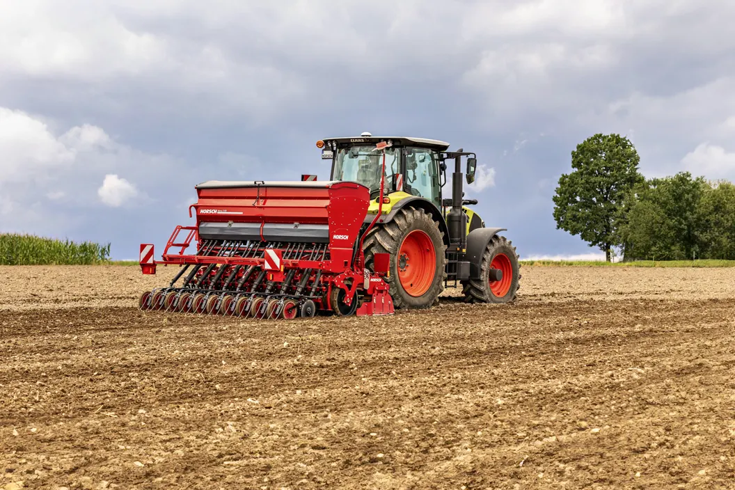 Grada rotativa Horsch Versa KR amb la tremuja de sembra, darrere d'un tractor, sobre terra acabada de treballar