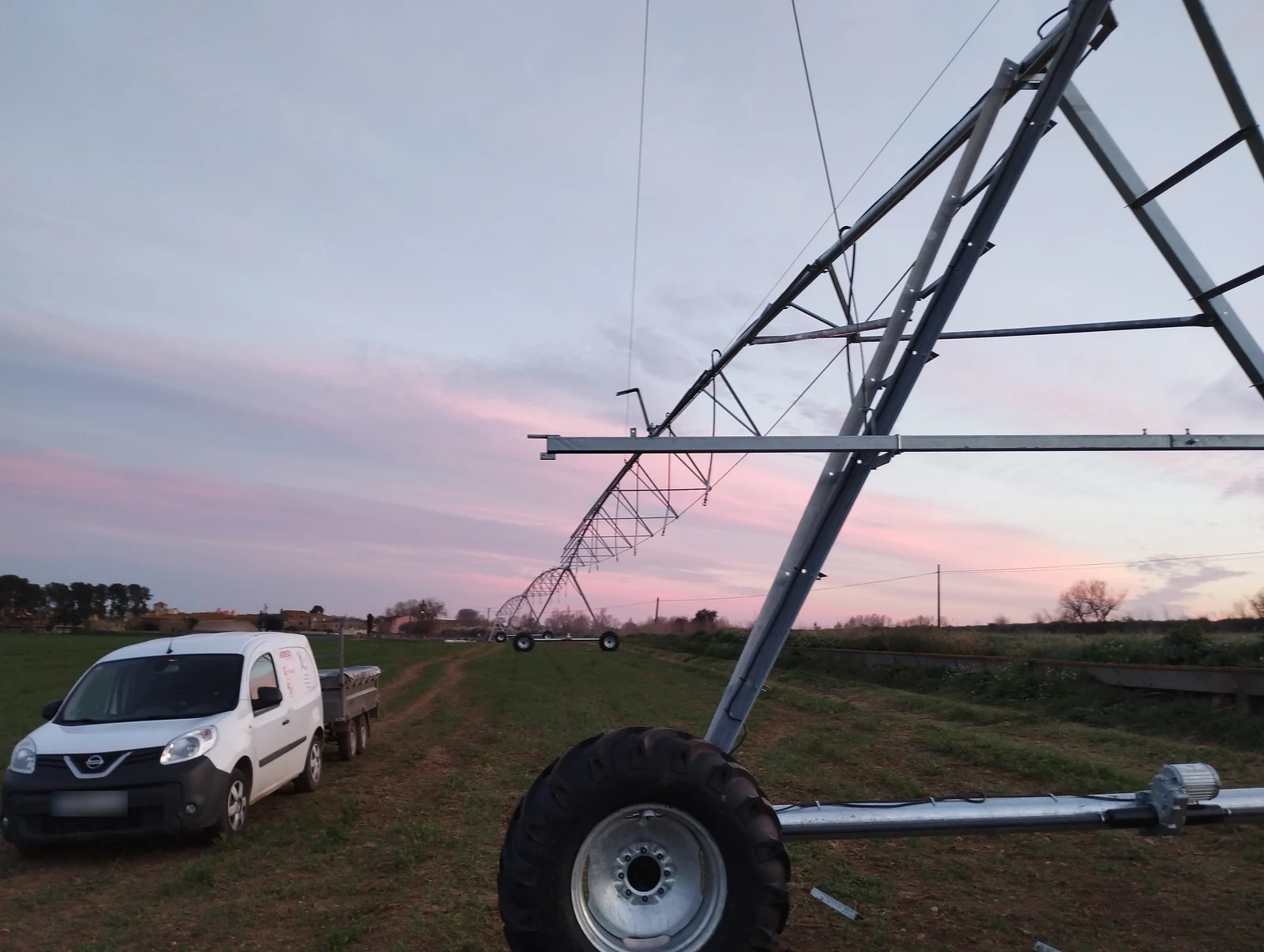 Una torre de pivot 2iE al capvespre, amb la resta del braç al fons i la furgoneta de XeviAgro amb un remolc al costat
